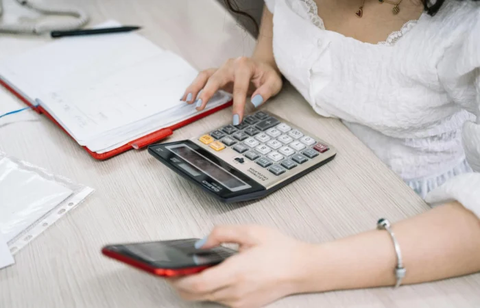 Księgowa wykonująca obliczenia na kalkulatorze i telefonie w biurze rachunkowym Sylwia Stelmasiewicz Księgowa wykonująca obliczenia na kalkulatorze i telefonie w biurze rachunkowym Sylwia Stelmasiewicz